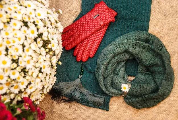 An artistic flat lay showing various types of scarves – silk, wool, and cotton – with different patterns and colors, neatly folded alongside basic fashion accessories like sunglasses and a handbag.