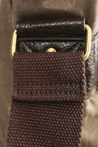A close-up of various belt materials: polished black leather, distressed brown leather, rough canvas, and a vibrant woven fabric, showcasing their unique textures.