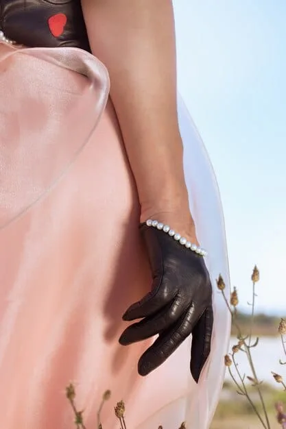 A close-up of a woman's hand adorned with a delicate diamond tennis bracelet, subtly illuminated, complementing a luxurious silk gown at a formal event.