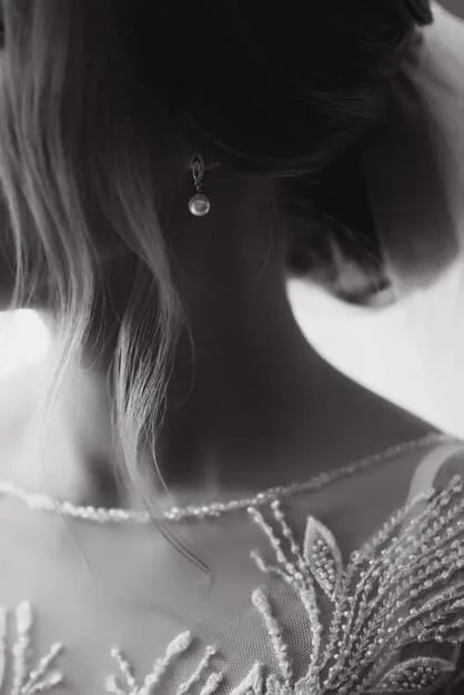 A detailed shot of an elegant woman's intricate updo, adorned with delicate crystal hairpins, complementing a neutral-toned formal dress, softly lit to highlight the textures.