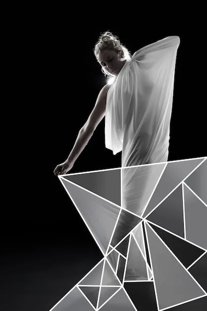 A fashion model wearing a sculptural dress with dramatic, sharp angles in contrasting black and white fabric, set against a minimalist white background to emphasize the garment's form.