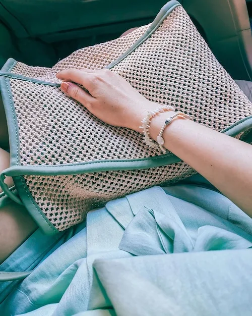 A close-up of a chic silk scarf intricately tied around the handle of a minimalist leather handbag, showcasing a sophisticated detail that elevates the accessory itself.