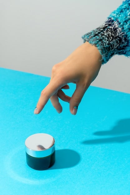 A person's hand carefully inspecting a small expiration icon on the bottom of a foundation bottle, with other makeup items blurred in the background.