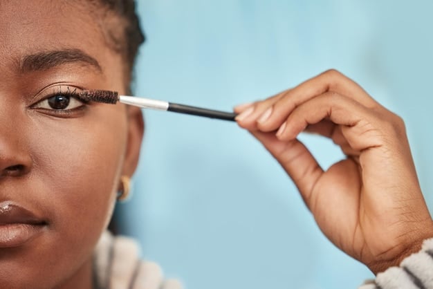 A person using a clear brow gel to brush up their eyebrows, showing the final step of setting with a soft focus on the defined brow.