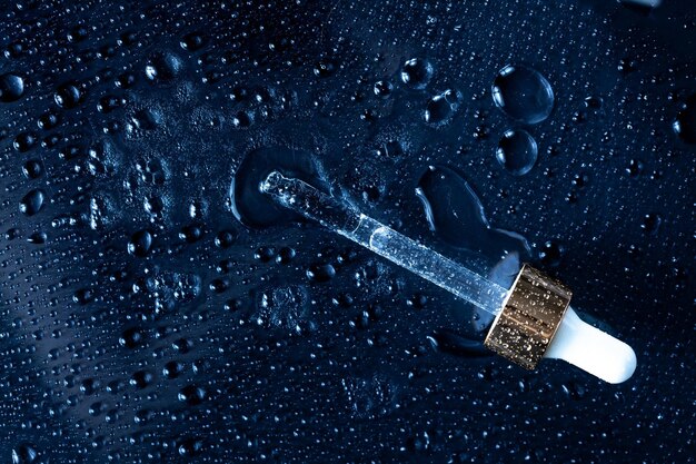 A close-up of a hyaluronic acid serum being dispensed, with water droplets surrounding the bottle, emphasizing its hydrating qualities. The setting is clean and clinical.