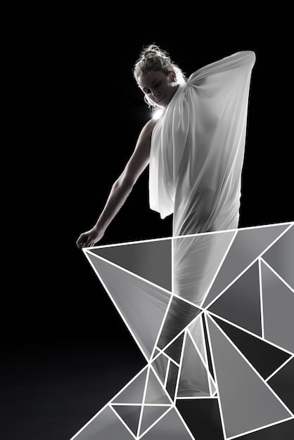 A fashion model wearing a sculptural dress with dramatic, sharp angles in contrasting black and white fabric, set against a minimalist white background to emphasize the garment's form.