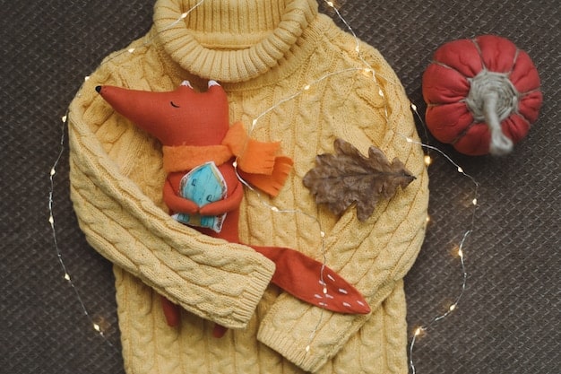 A fashion flat lay featuring clothes in warm color palettes—olive green, burnt orange, golden yellow, and cream—arranged to show harmonious combinations. Accessories like gold jewelry are also present.