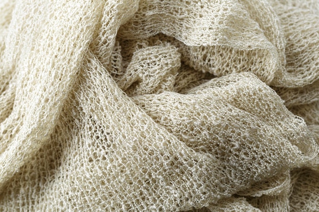 A close-up of a textured fabric, possibly a boucle knit or raw silk, in a muted, earthy tone with subtle metallic threads woven in, highlighting tactile luxury.