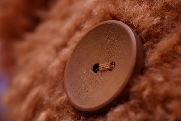 A close-up shot of a classic beige trench coat sleeve, showing the meticulous stitching, genuine horn buttons, and a well-crafted leather buckle detail, highlighting the quality and craftsmanship.