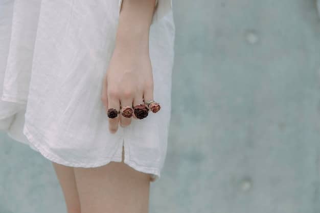 A close-up of a woman's hands adorned with multiple rings of various sizes and styles, showcasing a mix of metals and stones, with a minimalist background.