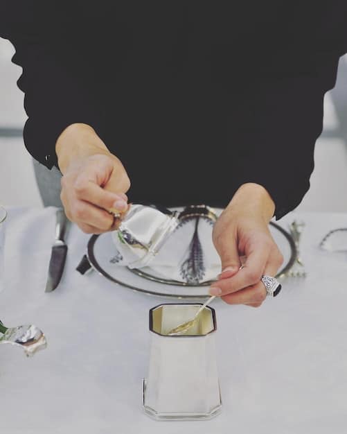 A jeweler meticulously resetting a diamond into a new platinum ring, with various tools and different settings on a velvet tray beside them.