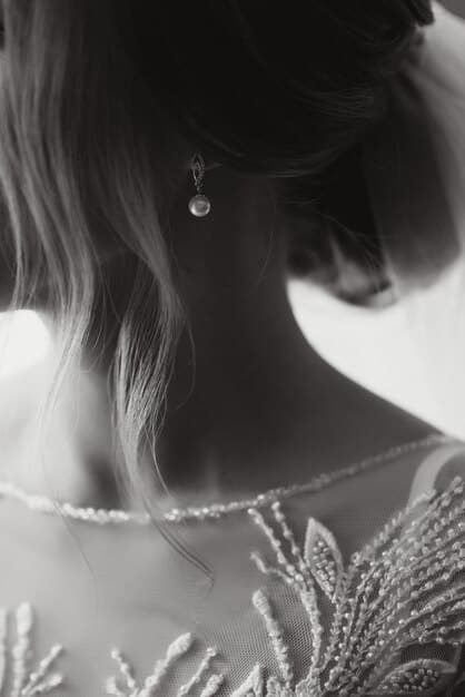 A detailed shot of an elegant woman's intricate updo, adorned with delicate crystal hairpins, complementing a neutral-toned formal dress, softly lit to highlight the textures.